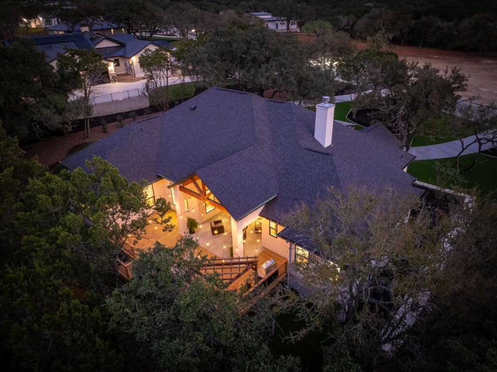 Aerial view at dusk of the 8179 Blue Oak Way custom home among oak trees