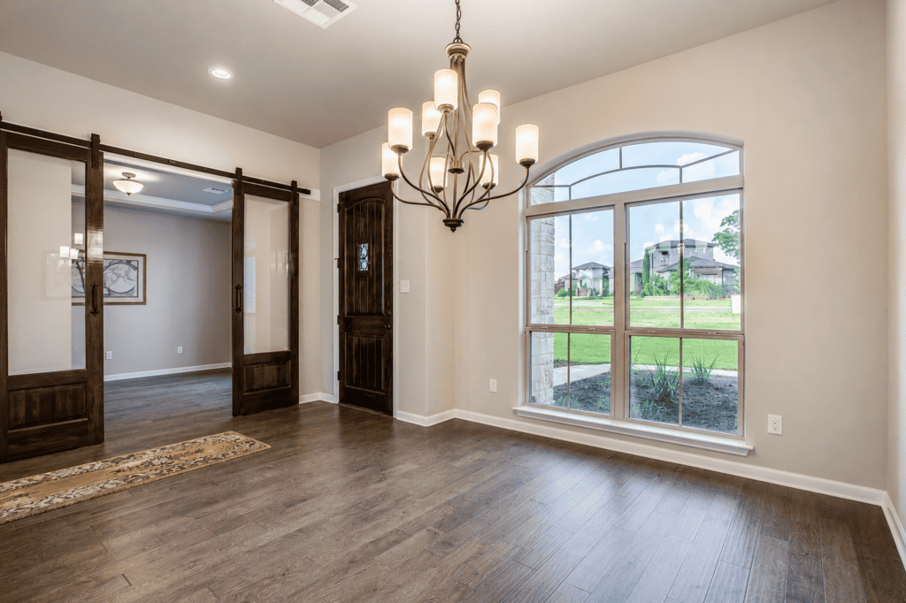 Dining room with sliding barn doors and arched window in the 1195 Via Principale custom home