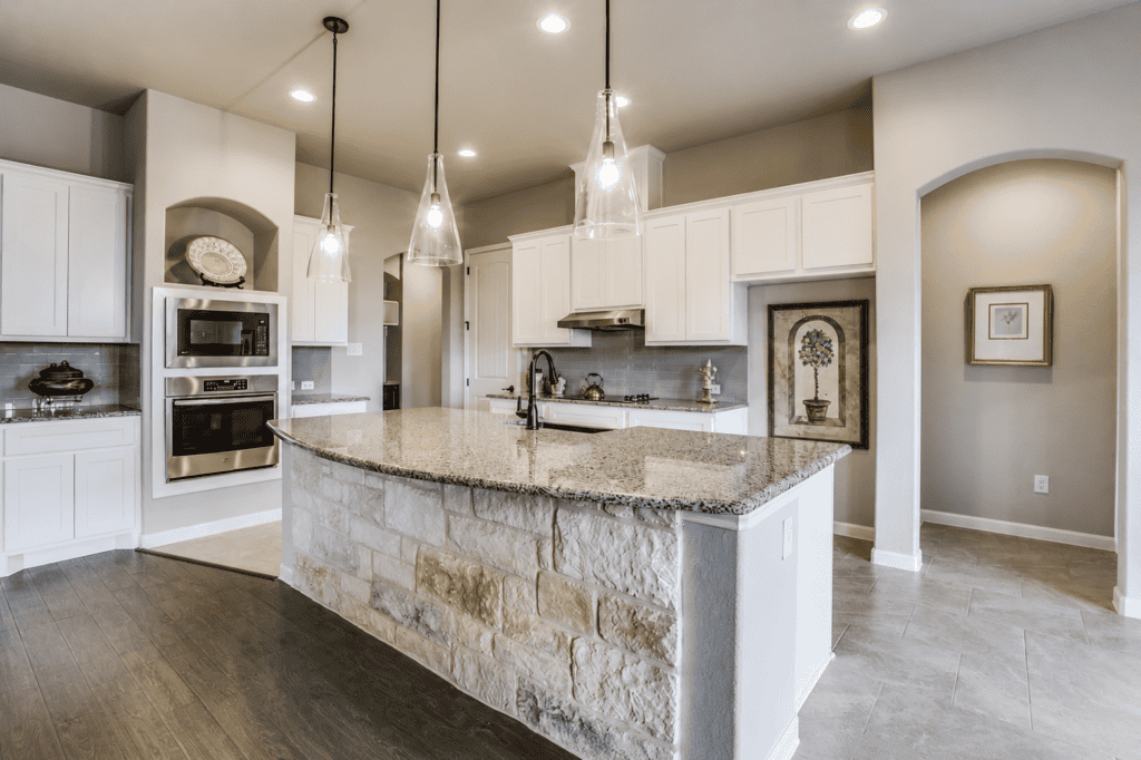 Kitchen with curved granite island and stainless appliances in the 1195 Via Principale custom home